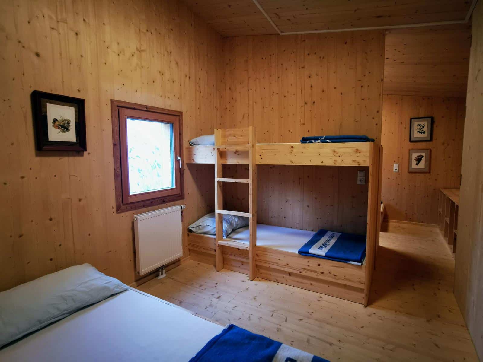 Zimmer auf Almhütte mit Betten aus Holz und Holzverkleidung