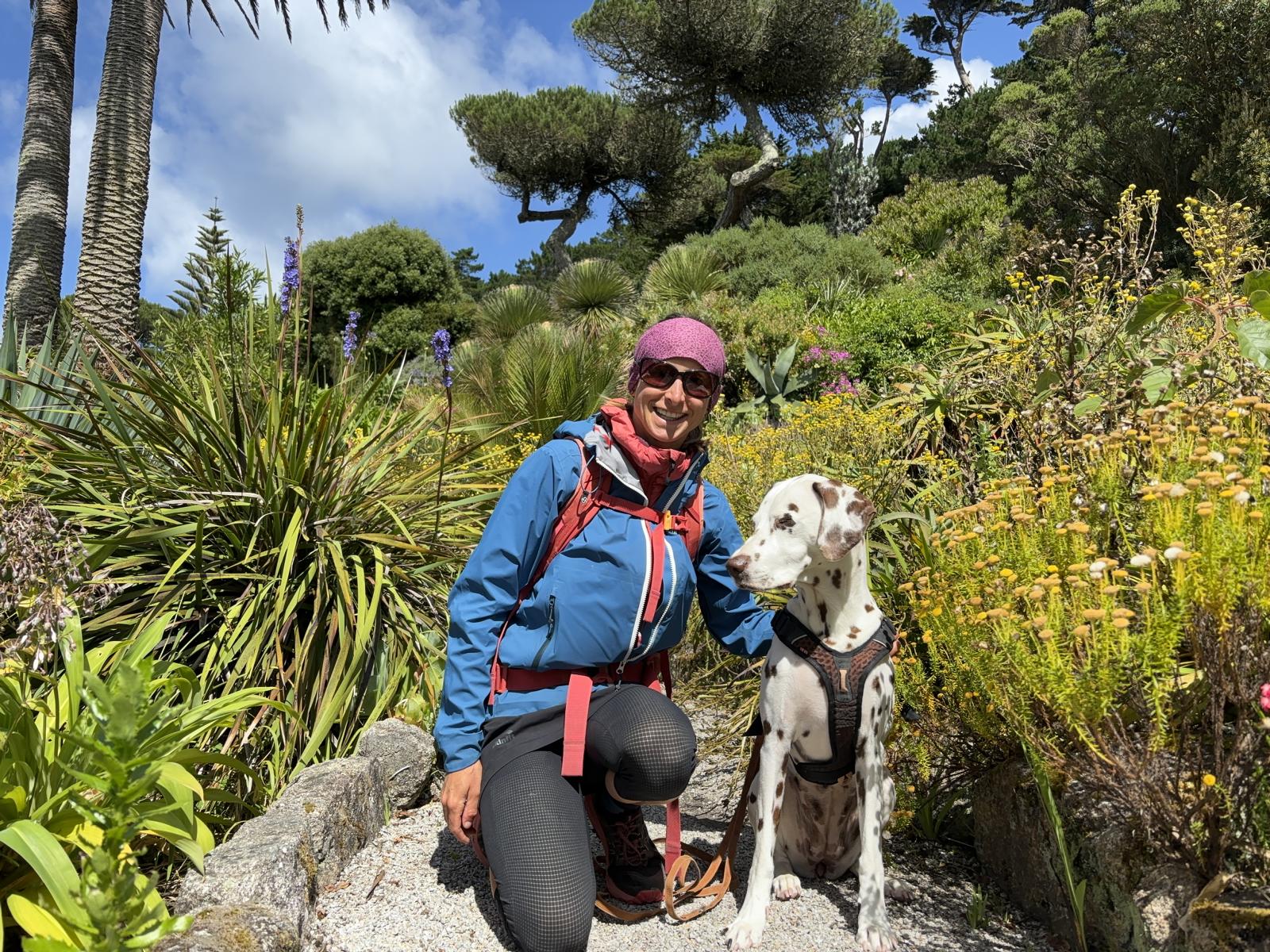 Frau in Wanderkleidung mit Hund (Dalamtiner) sitzen auf einem Pfad durch tropische Vegetation