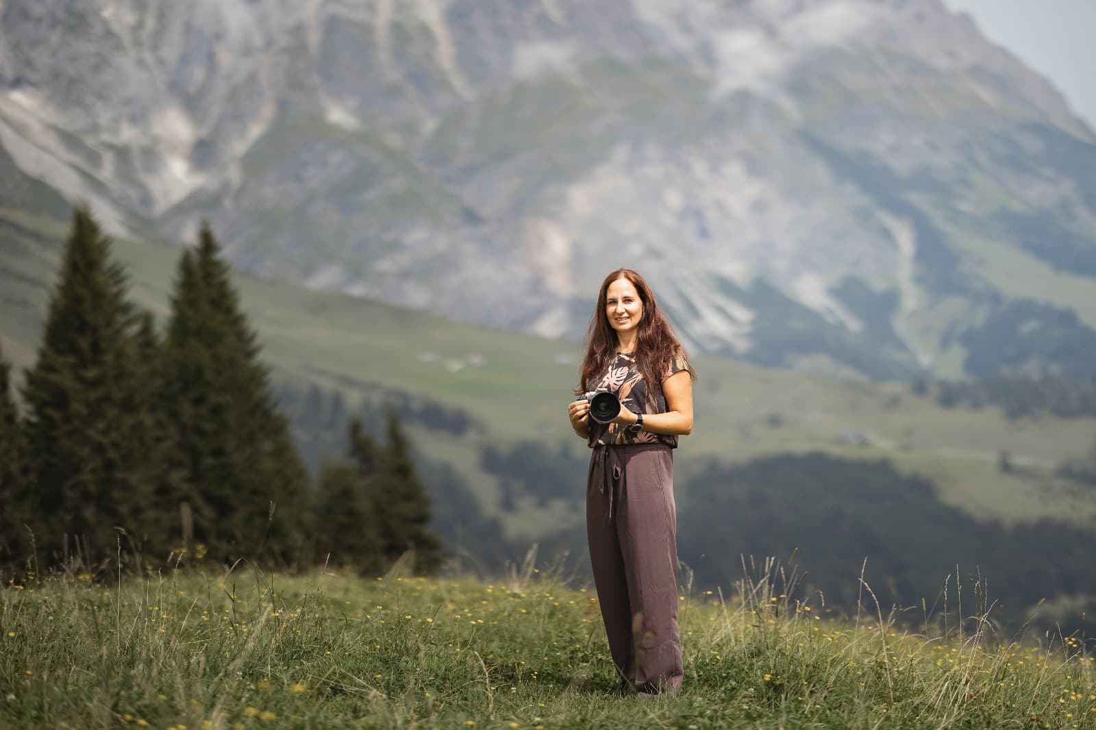 Eine Fotografin steht mit ihrer Kamera vor einer Bergkulisse