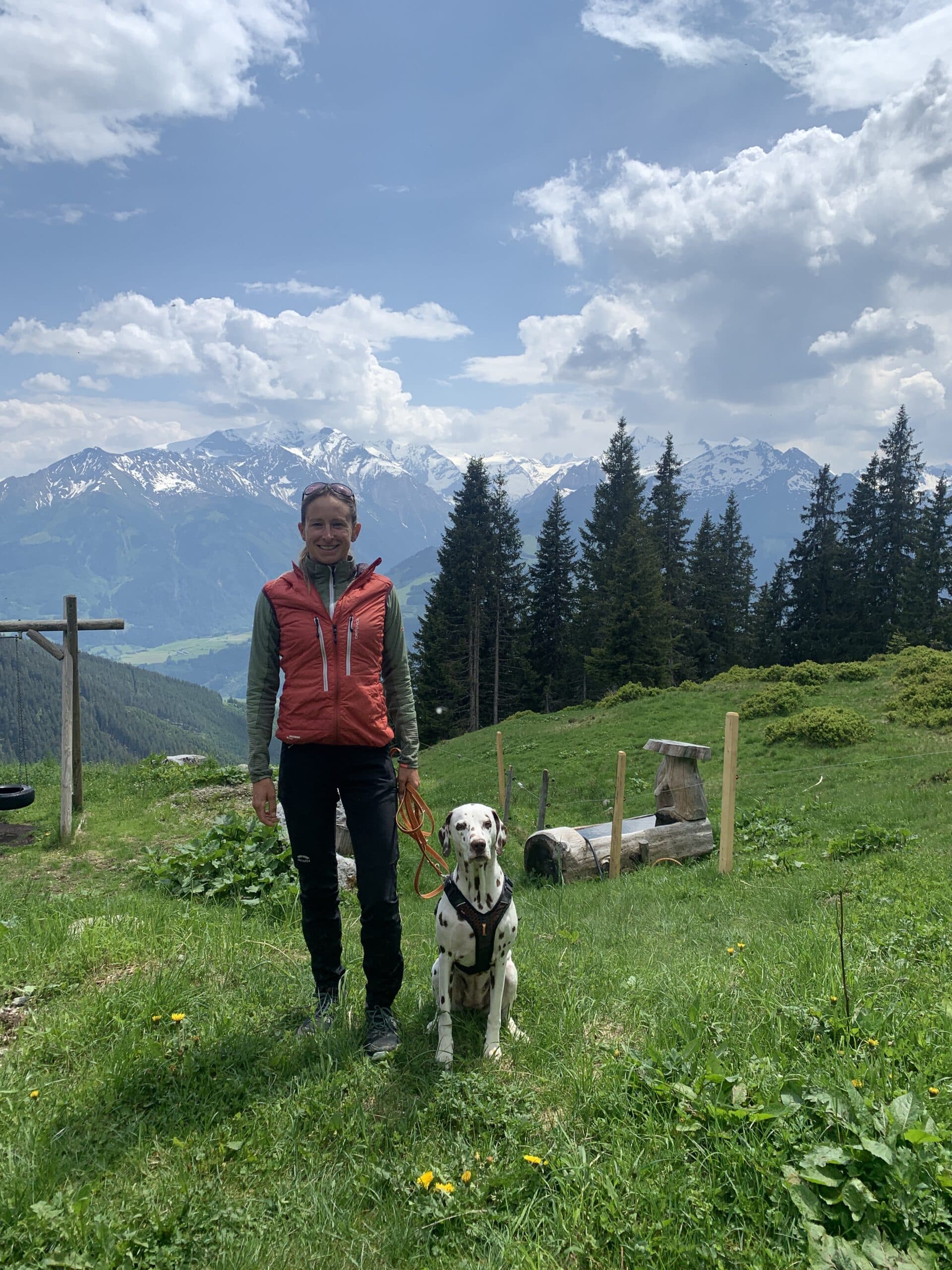 Frau steht mit Hund auf Bergwiese