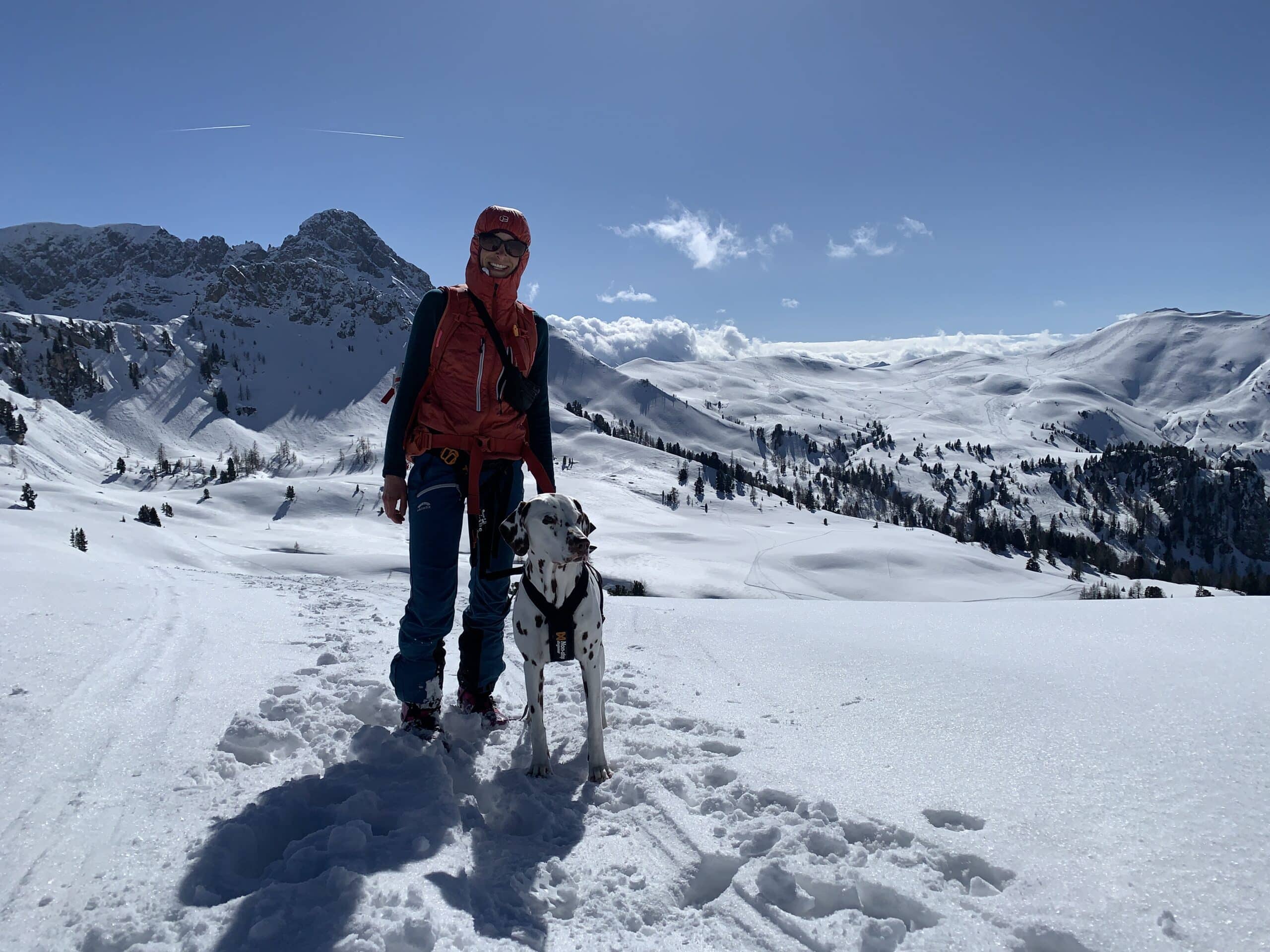 Frau mit Hund in sonniger Winterlandschaft im Gebirge