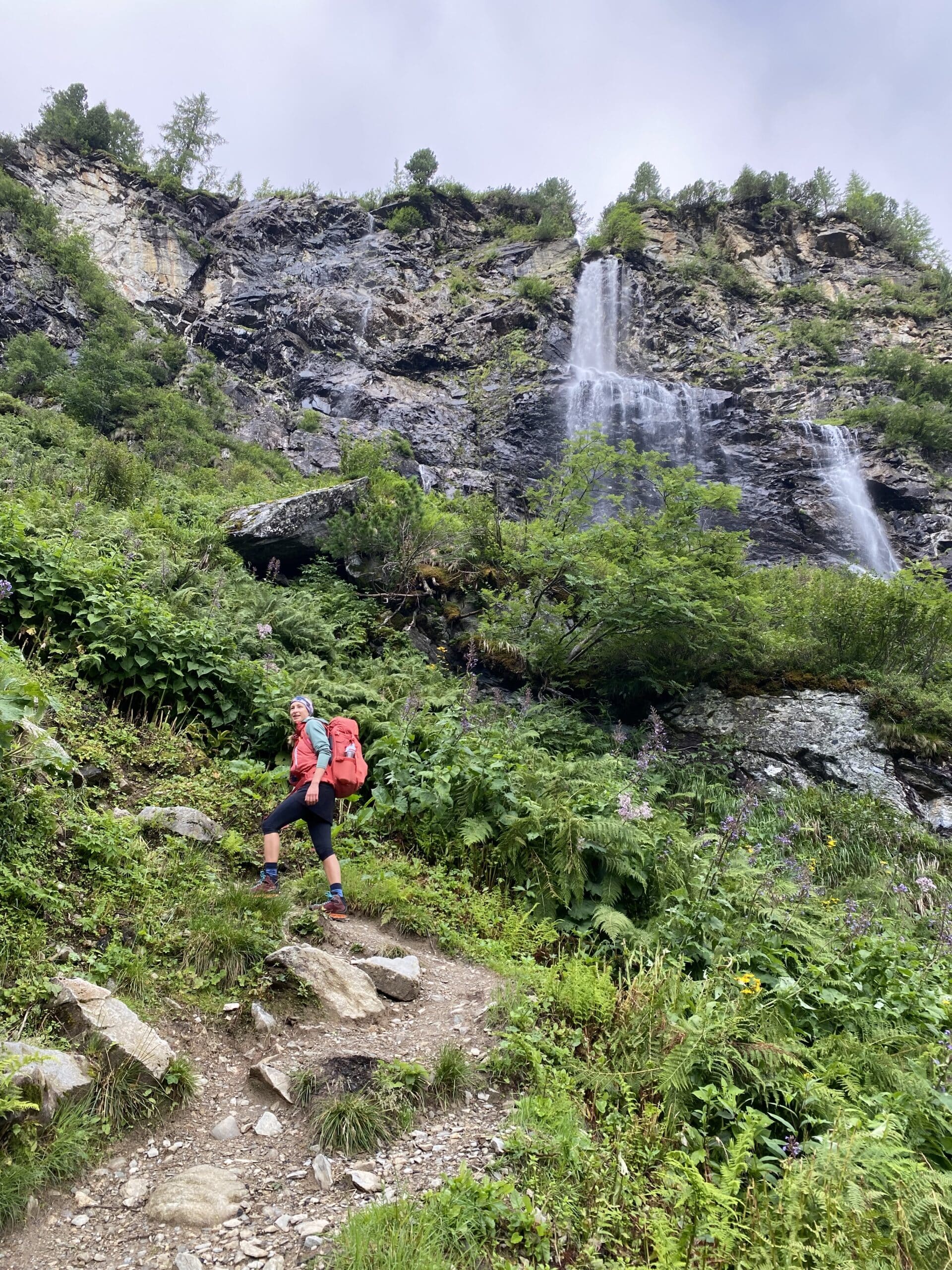 Frau wandert auf alpinem Steig, Felsen, Wasserfall