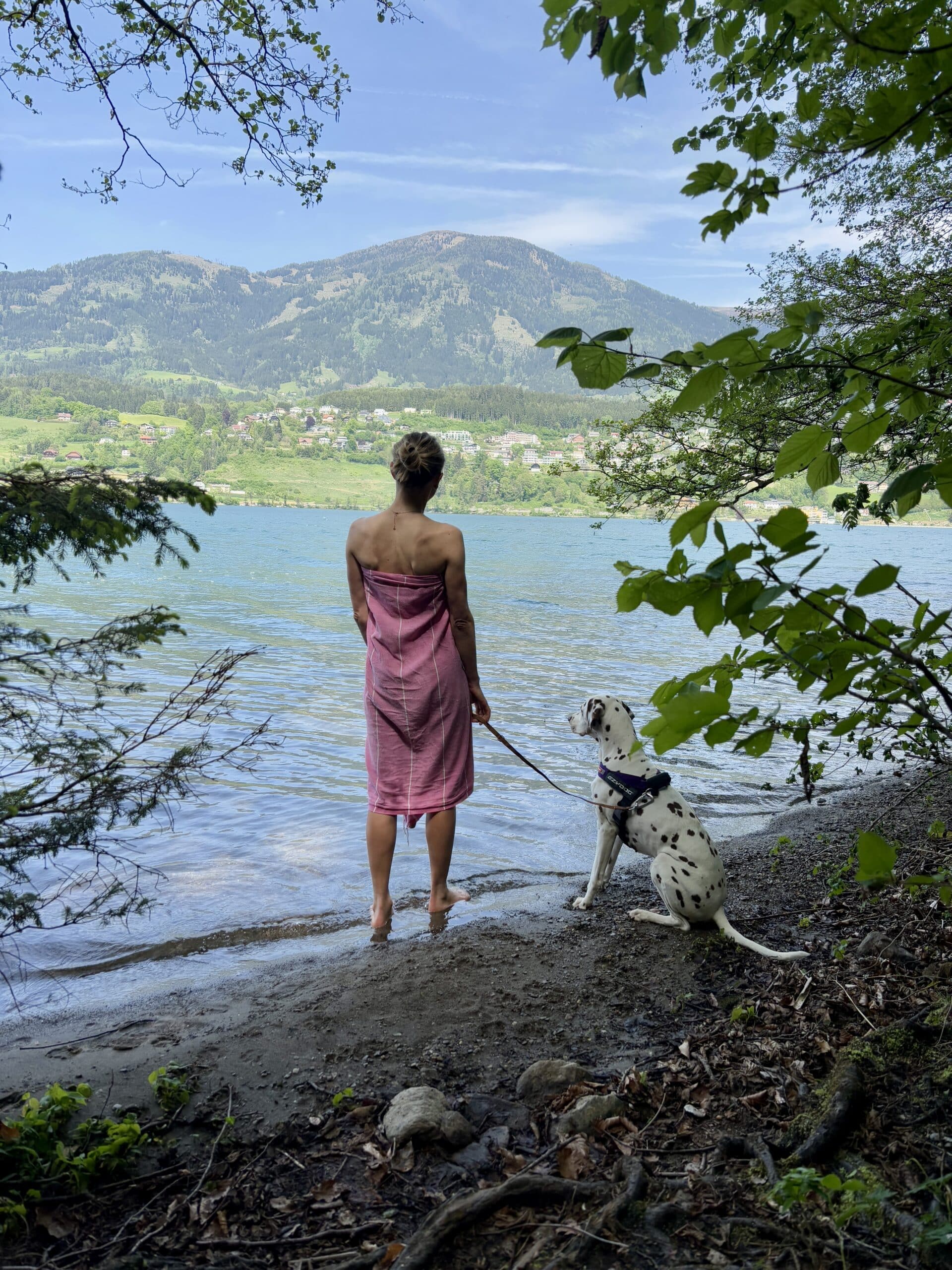 Frau steht mit Handtuch und Hund an der Leine am Südufer Millstätter See Slow Trail