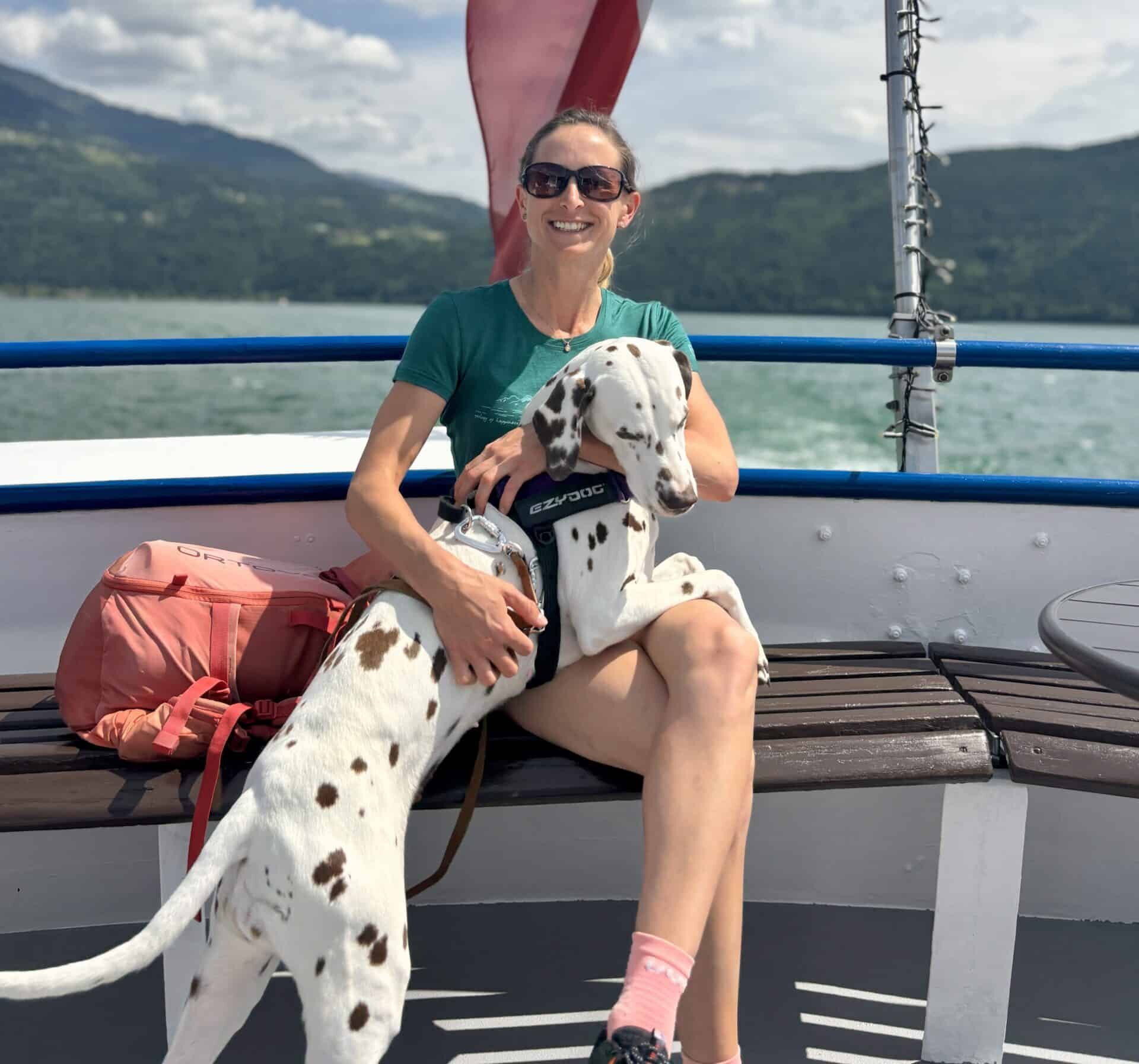 Frau sitzt mit Dalmatiner-Hund auf Schiff