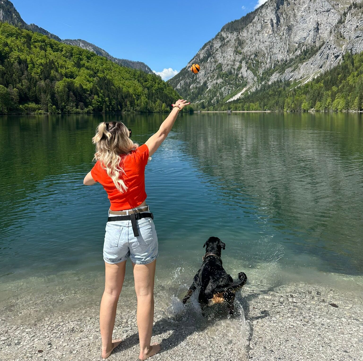 Frau wirft ihrem HUnd Stöckchen am Leopoldsteiner See