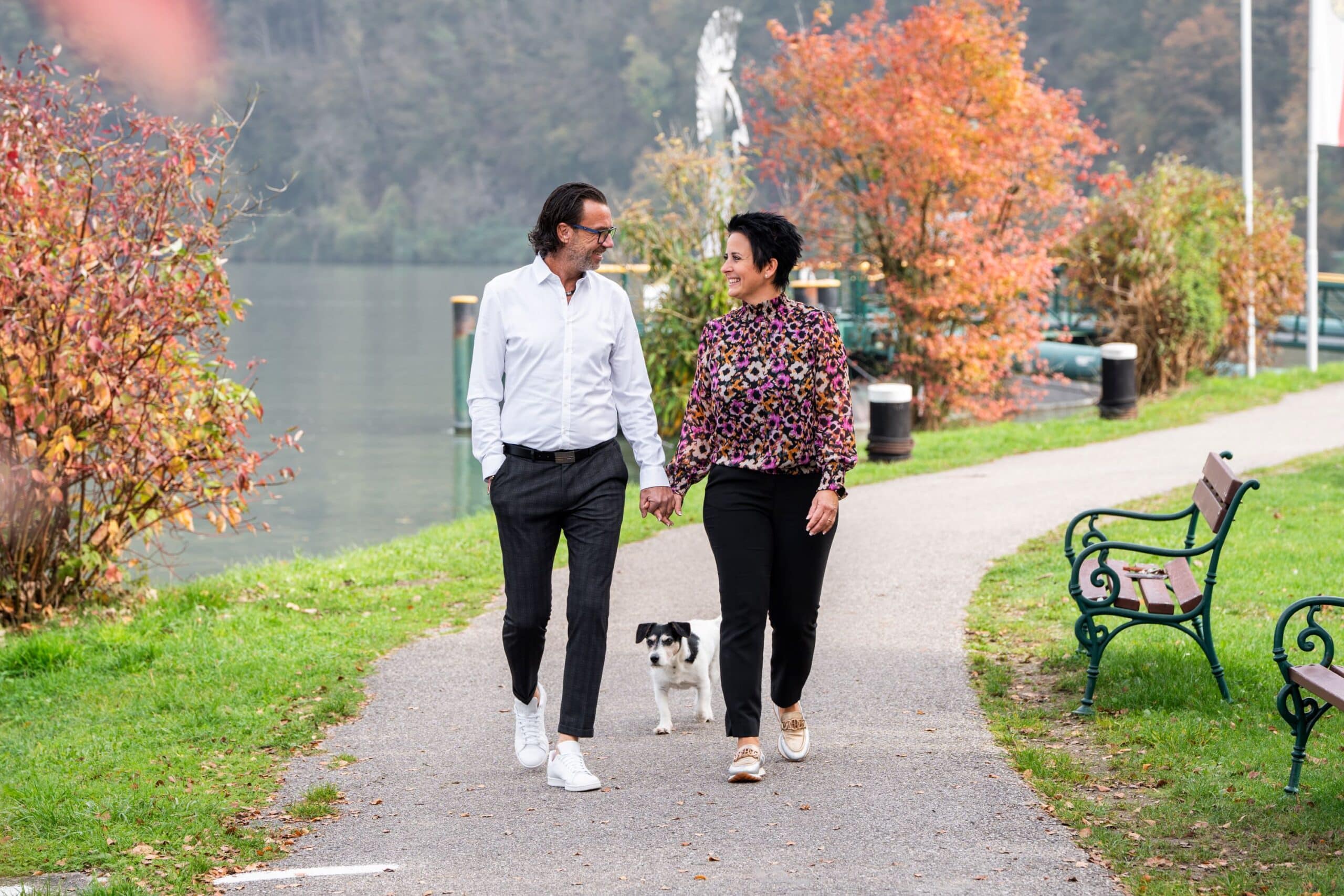 Frau und Mann spazieren mit Hund am Donauufer; Riverresort Donauschlinge