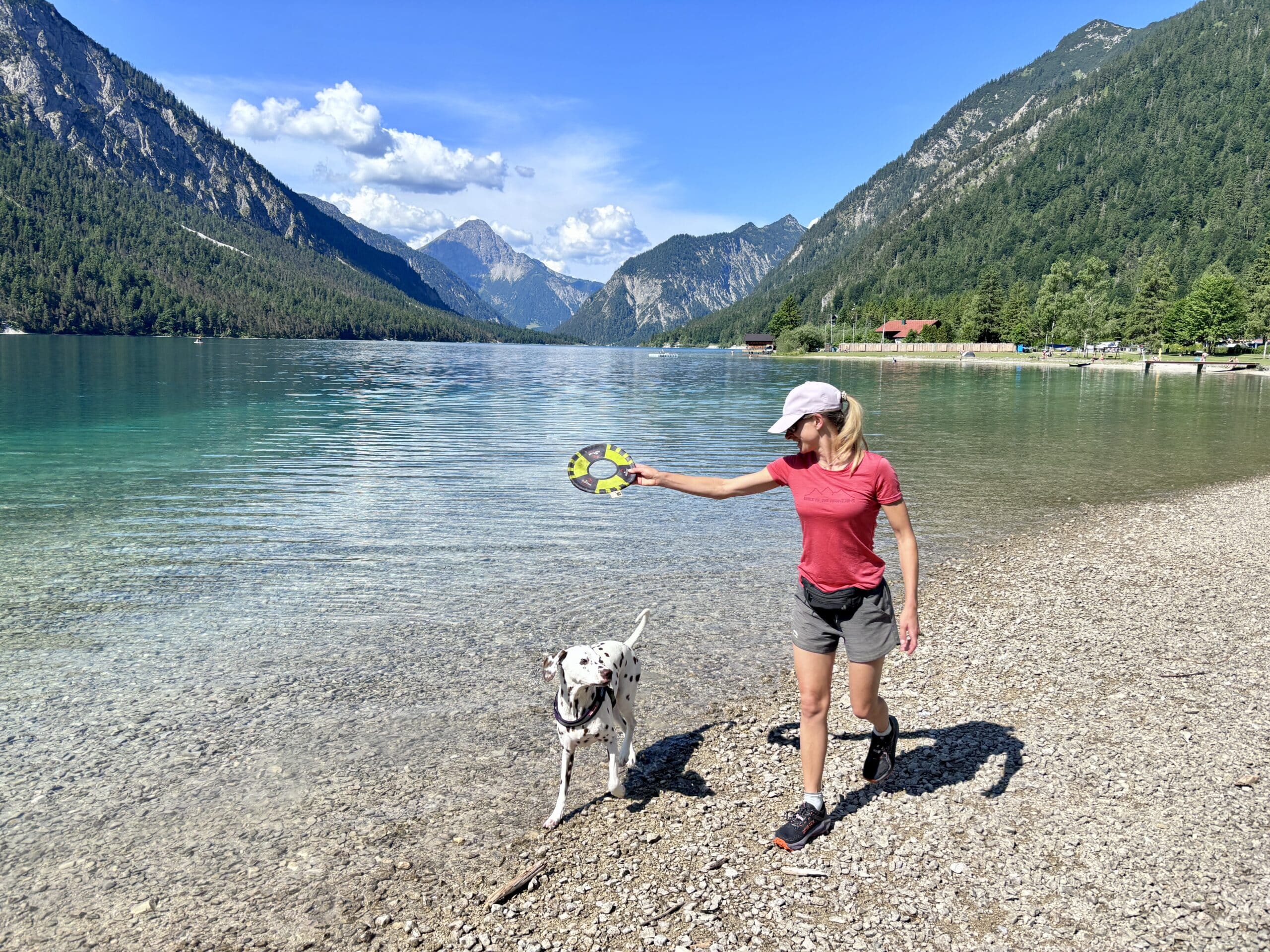Frau spielt mit Hund am Hundestrand Plansee Tirol Sennalpe
