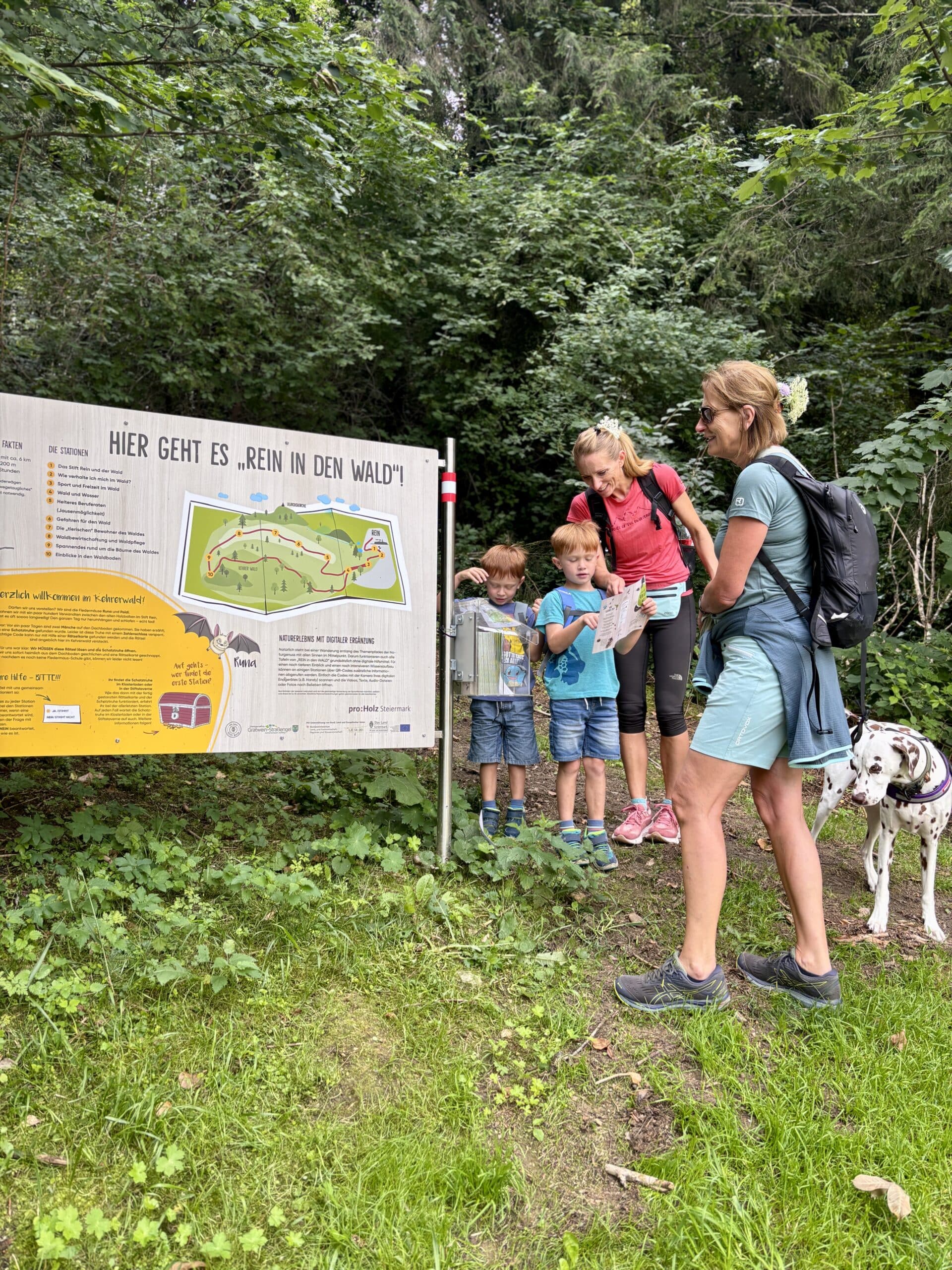 Erlebnispfad Rein in den Wald; Rein bei Graz; Familie mit Hund vor Infotafel