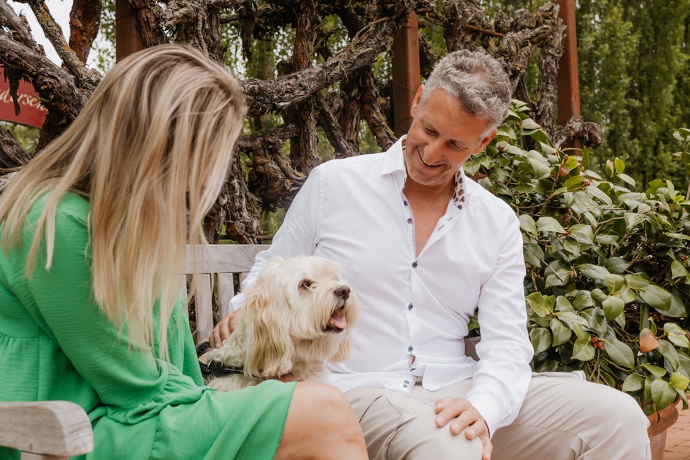 das Eisenberg, Pärchen sitzt mit Hund im Garten auf Parkbank