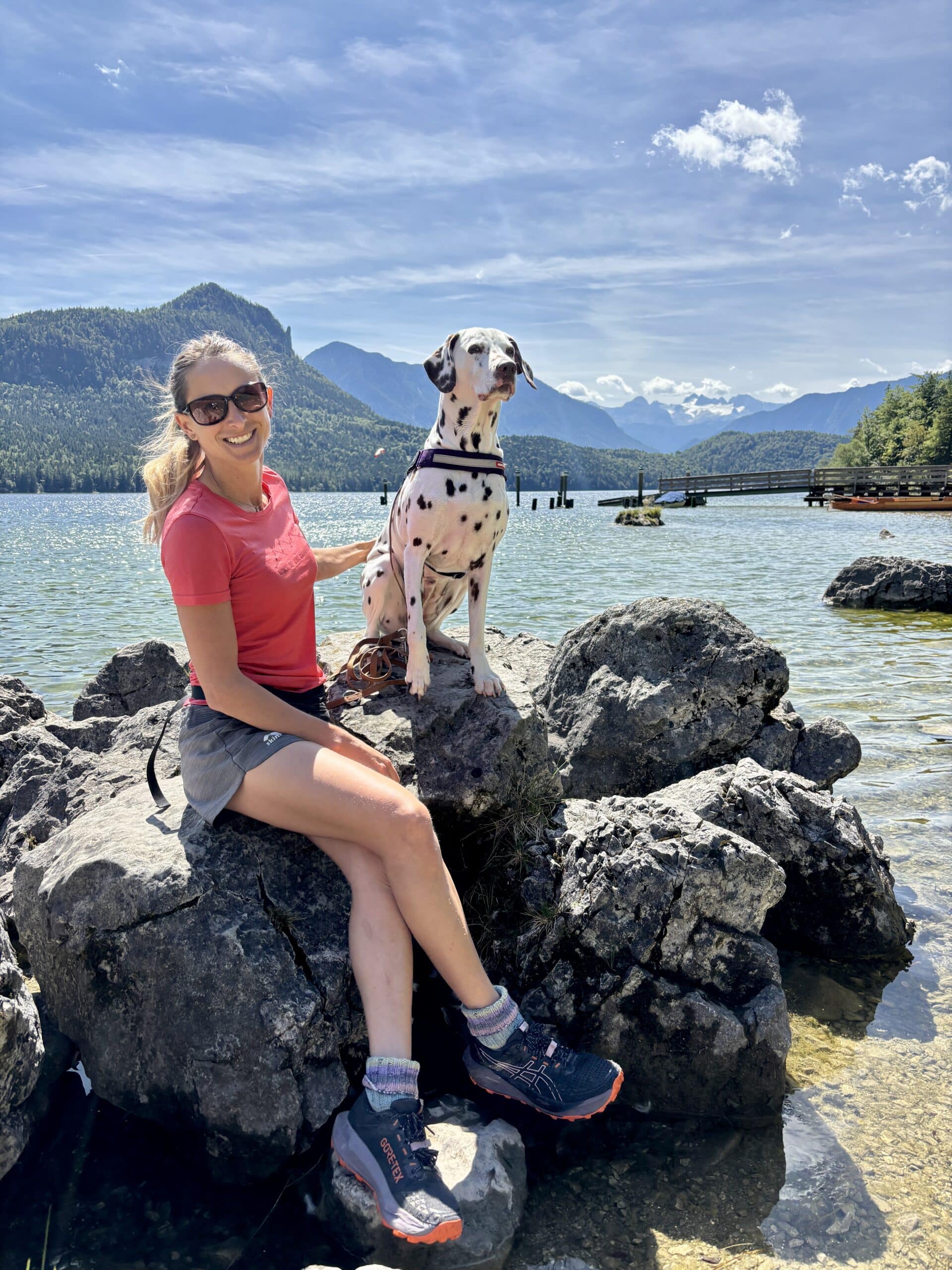 Frau sitzt mit Hund auf Felsen am Altausseer See
