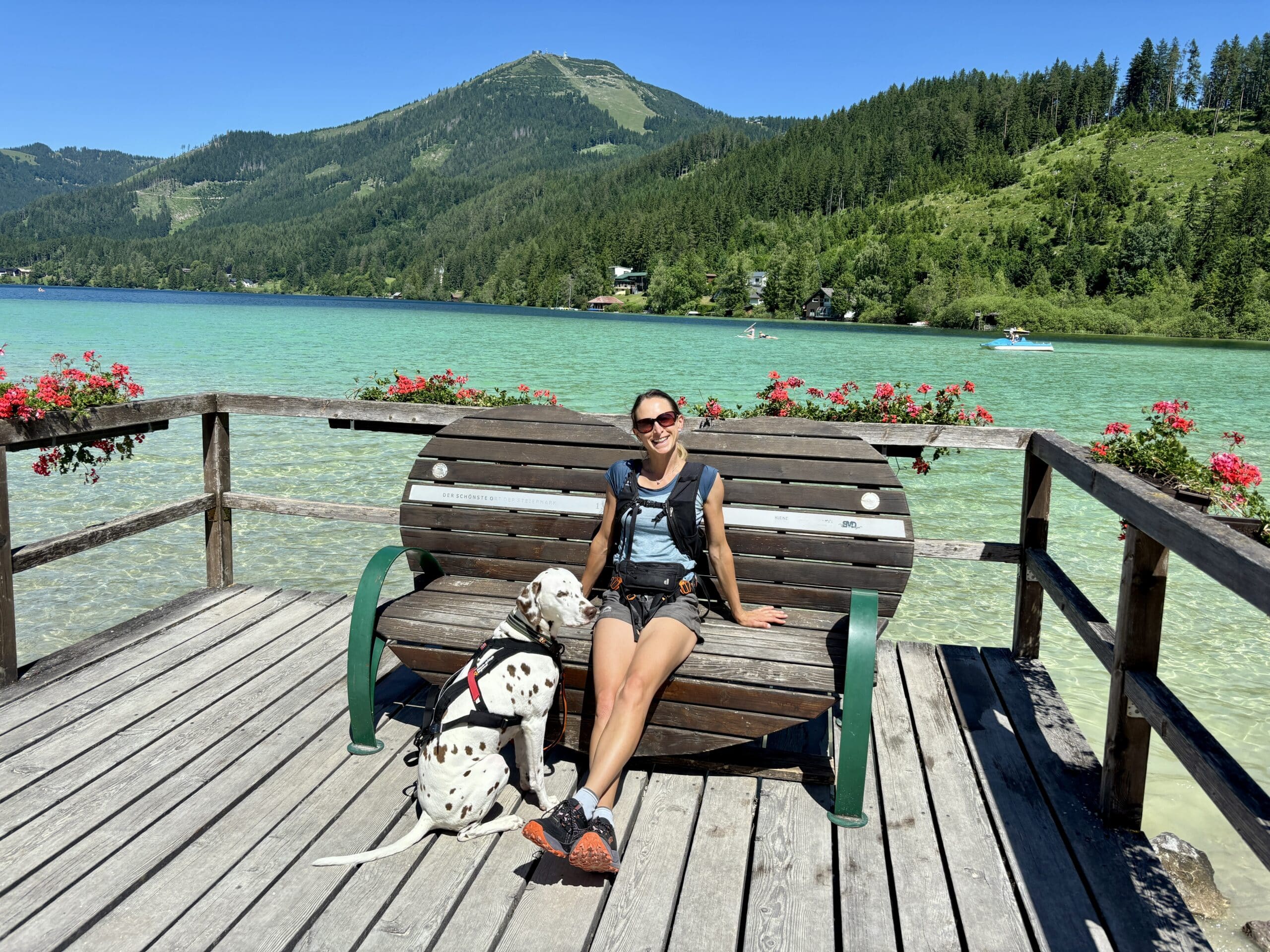 Rundwanderweg Erlaufsee Steiermark; Frau sitzt auf Bank am See, Hund sitzt daneben