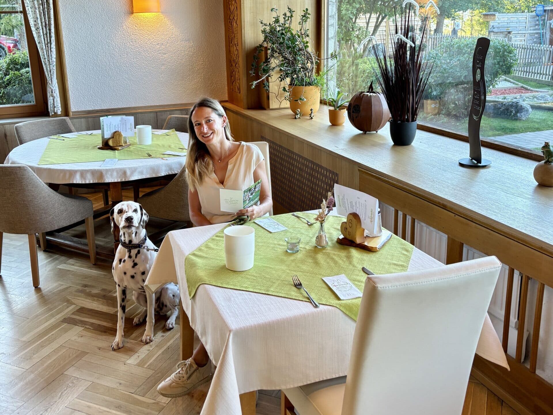 Restaurant Hundehotel Almfrieden; Frau mit Hund am Tisch