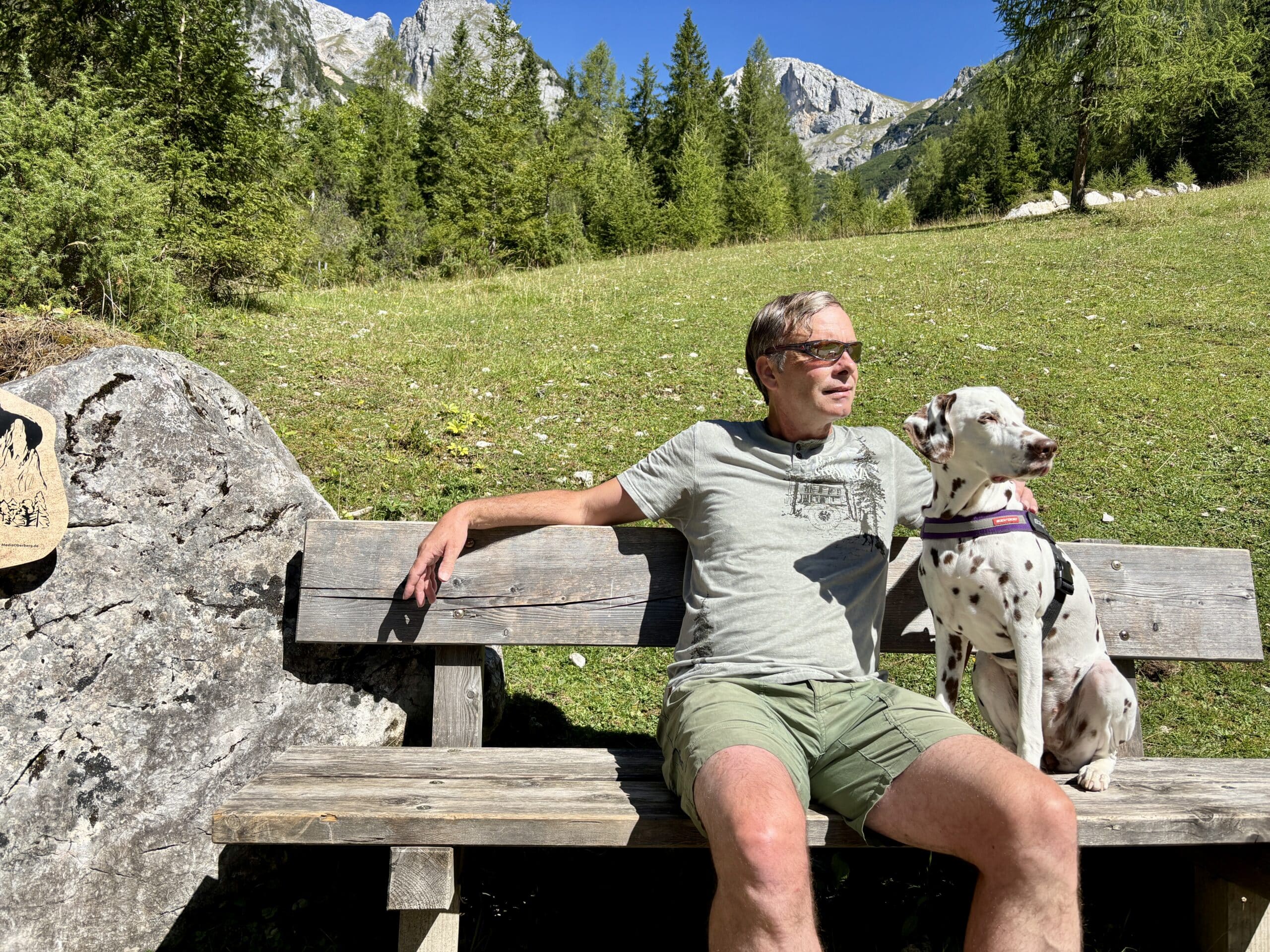 Mann mit Hund macht Rast auf einer Bank am Weg zur Lärchbodenalm