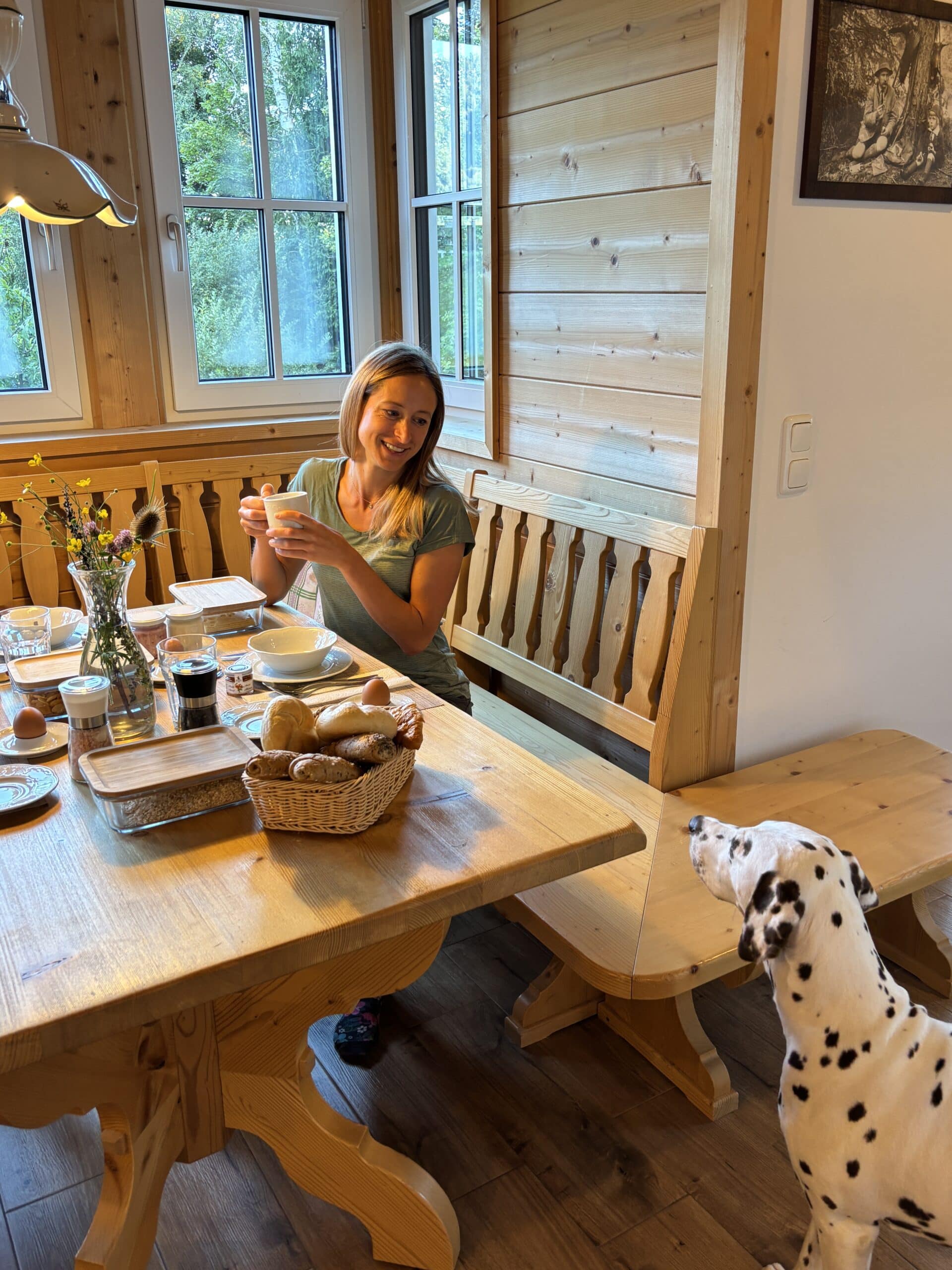 Frau mit Hund am Frühstückstisch im Chalet; Urlaub mit Hund im Narzissendorf Zloam