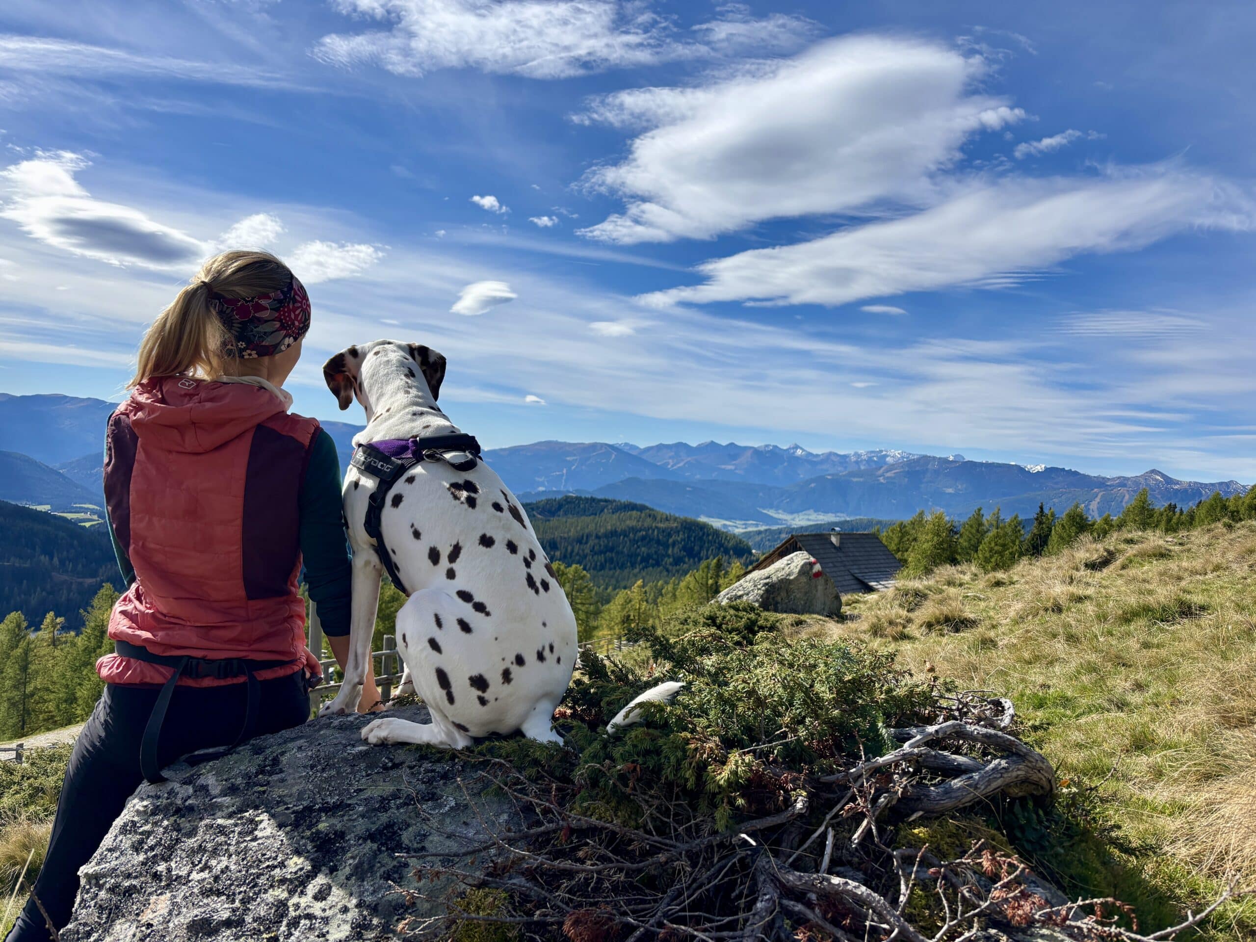 Urlaub mit Hund im Lungau; Frau sitzt mit Hund auf Felsen, Blick ins Tal
