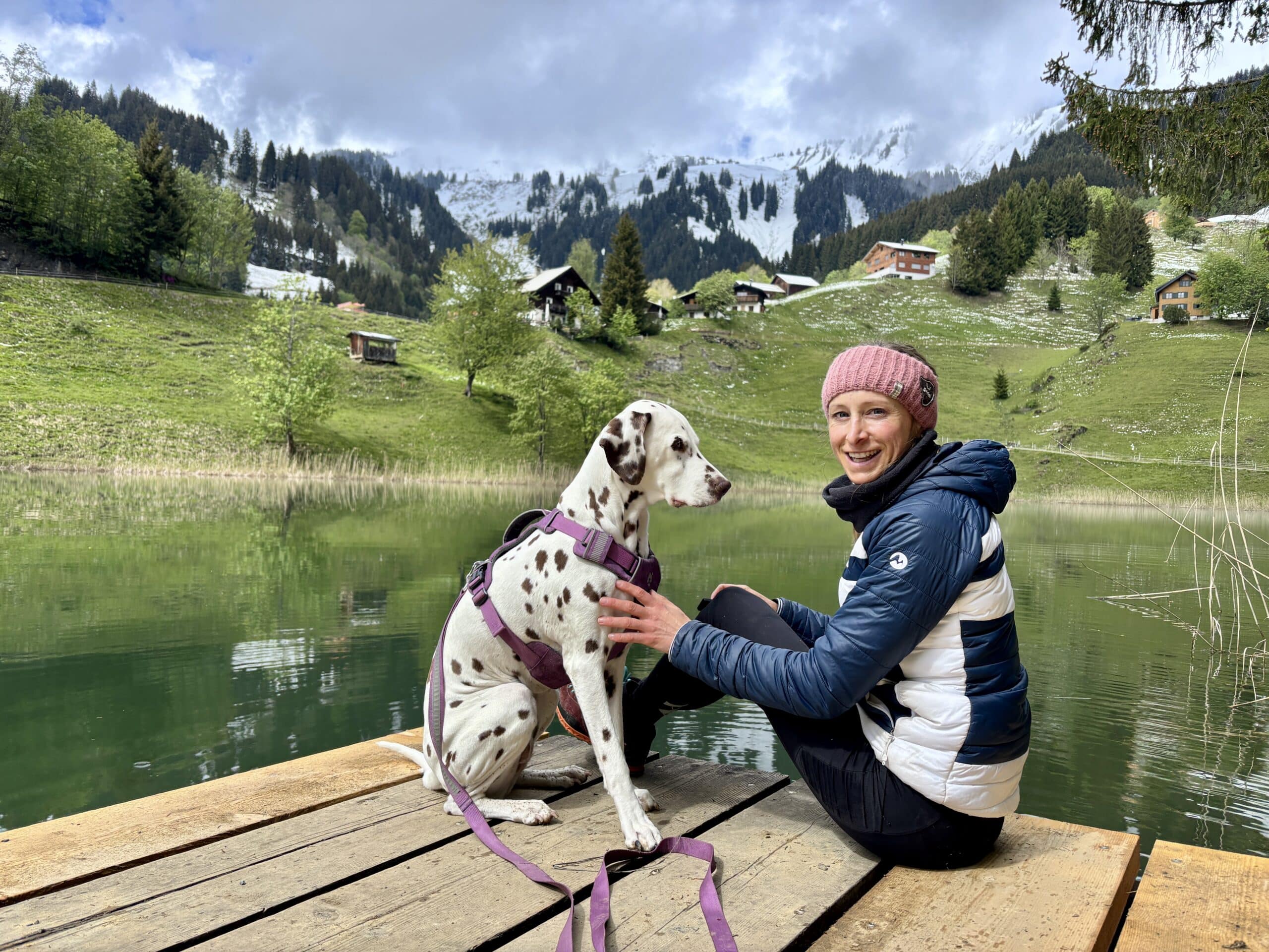 Seewaldsee mit Hund; Frau sitzt mit Hund auf Holzsteg am See
